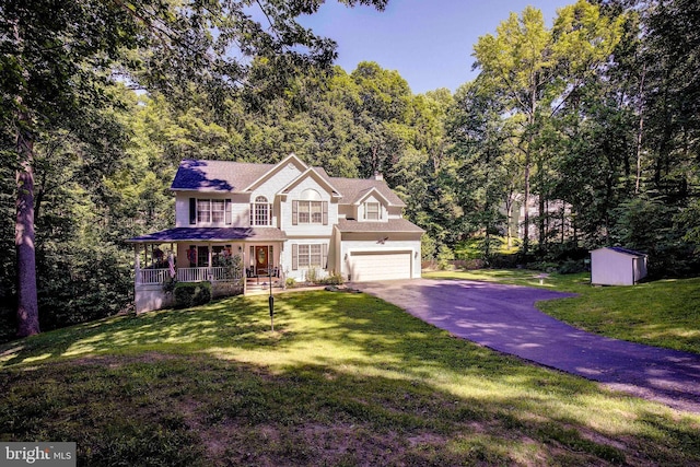 colonial home with a porch, a garage, a storage shed, and a front lawn