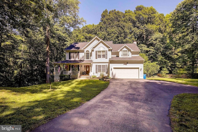 view of front of house featuring a garage, covered porch, and a front lawn