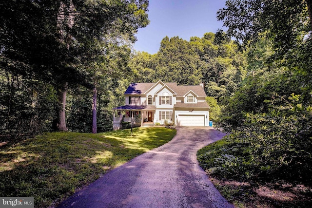 colonial-style house featuring a garage, a front lawn, and covered porch