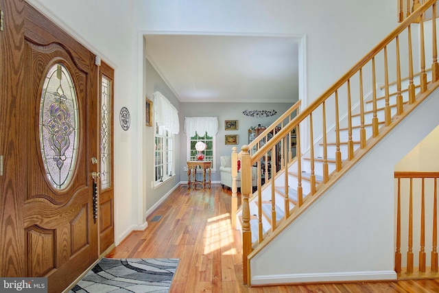 foyer entrance with crown molding and light hardwood / wood-style flooring