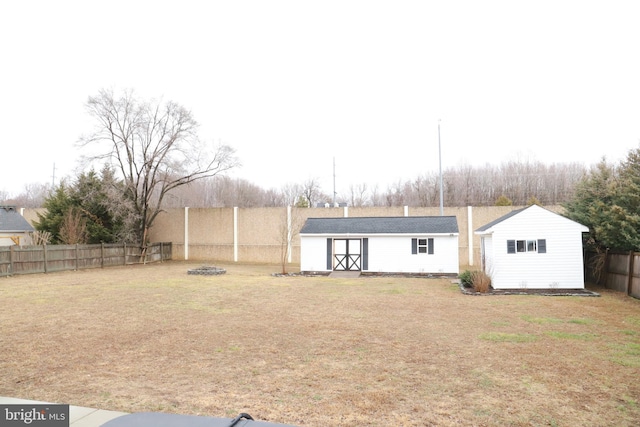 back of property featuring a shed, a yard, and a fire pit