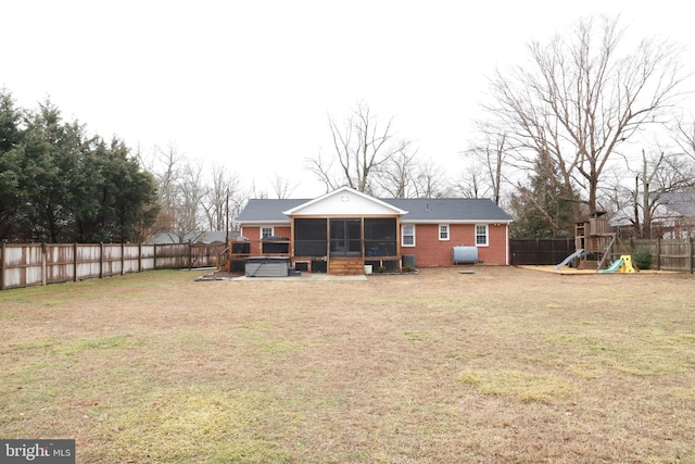 back of house with a playground, a sunroom, a yard, and a jacuzzi