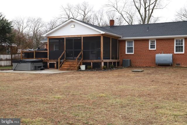 rear view of property featuring a lawn, central air condition unit, a hot tub, a sunroom, and a patio area