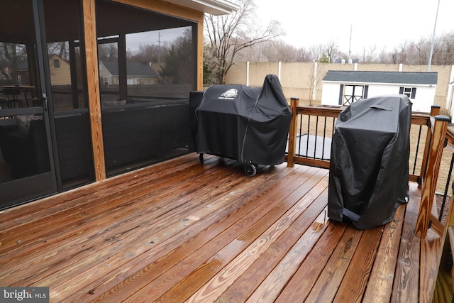 wooden terrace featuring grilling area and a storage unit