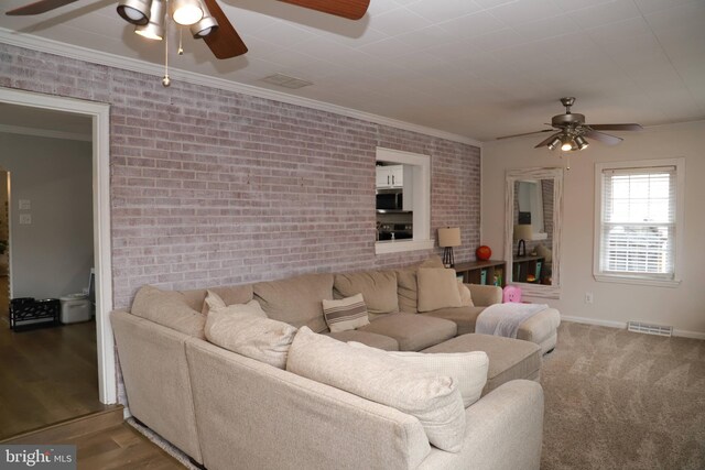 living room featuring crown molding, brick wall, wood-type flooring, and ceiling fan