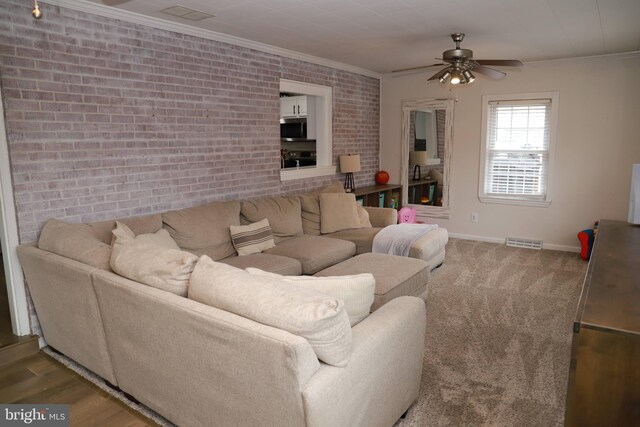 living room with ceiling fan, brick wall, and ornamental molding