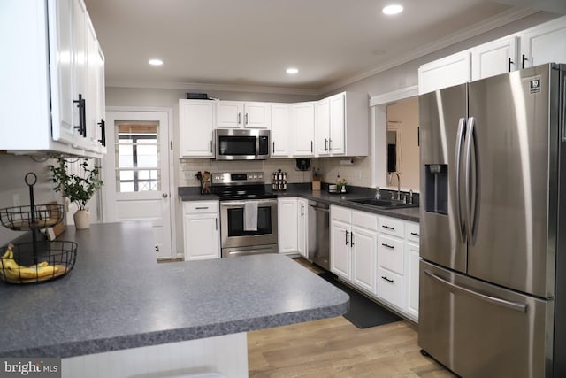 kitchen with stainless steel appliances, white cabinetry, sink, and kitchen peninsula