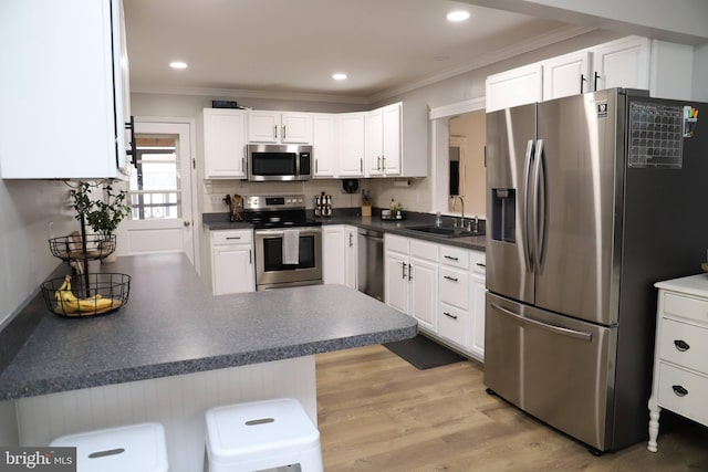 kitchen featuring sink, a breakfast bar area, white cabinetry, stainless steel appliances, and kitchen peninsula