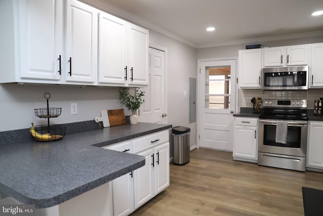 kitchen featuring crown molding, appliances with stainless steel finishes, white cabinetry, backsplash, and light hardwood / wood-style floors