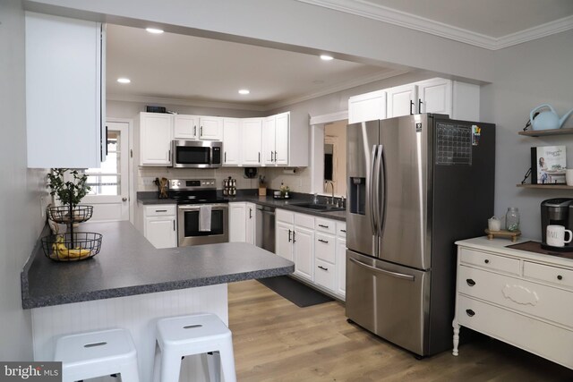 kitchen with a breakfast bar area, stainless steel appliances, and white cabinets