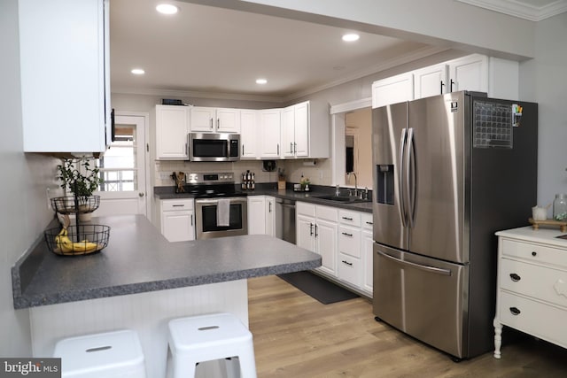 kitchen with white cabinetry, sink, a breakfast bar area, kitchen peninsula, and stainless steel appliances