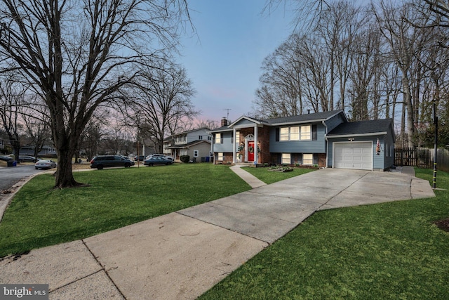 raised ranch featuring a garage and a yard