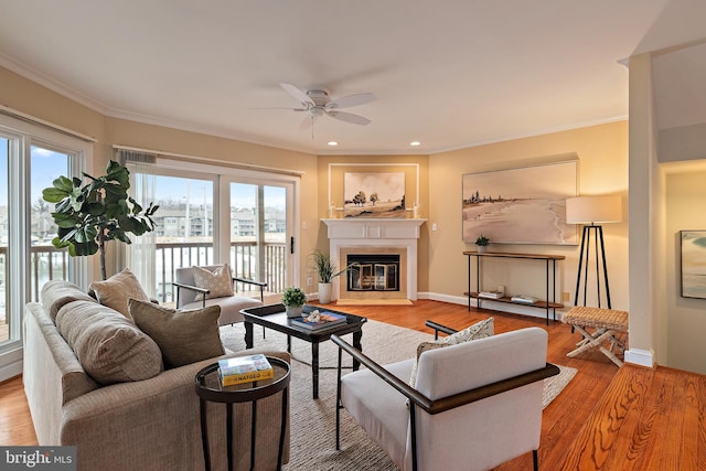 living room with baseboards, light wood-type flooring, a fireplace with flush hearth, and crown molding