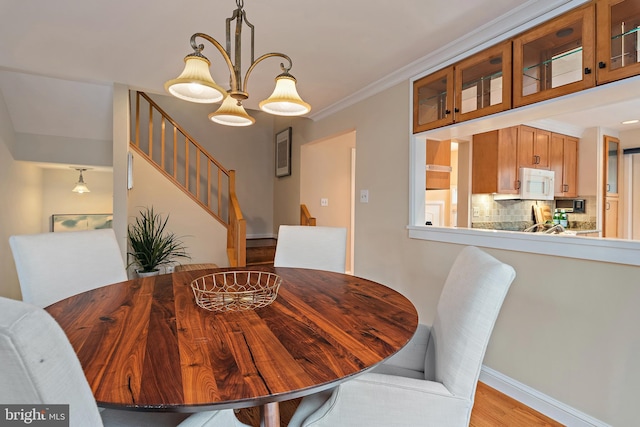 dining room featuring stairs, light wood finished floors, baseboards, and crown molding