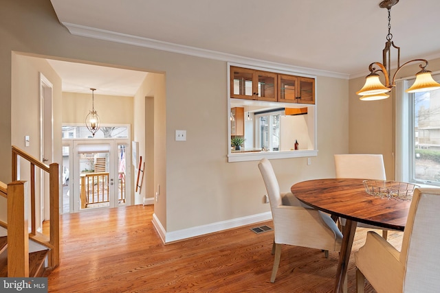 dining area with light wood finished floors, visible vents, stairway, ornamental molding, and baseboards