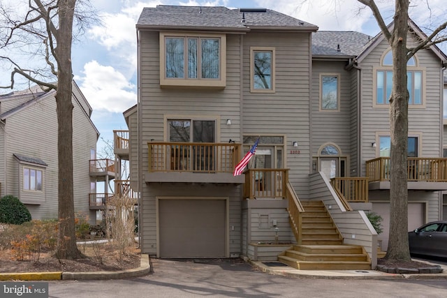 view of front of home featuring aphalt driveway, roof with shingles, an attached garage, and stairs