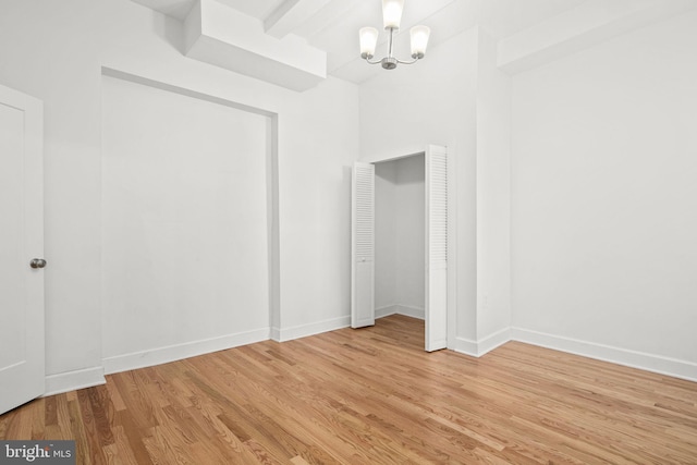 spare room with light hardwood / wood-style flooring and a notable chandelier