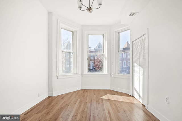 spare room with an inviting chandelier and light wood-type flooring