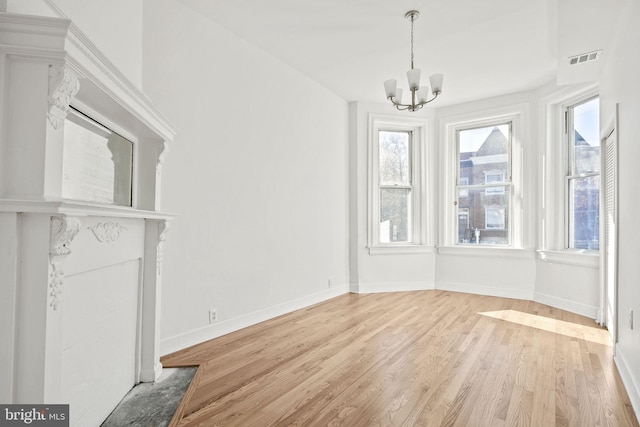 unfurnished dining area featuring a chandelier and light hardwood / wood-style flooring