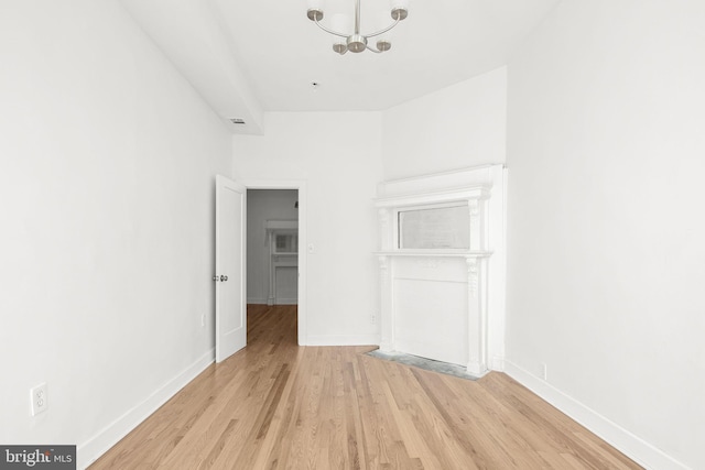 spare room featuring an inviting chandelier and light wood-type flooring