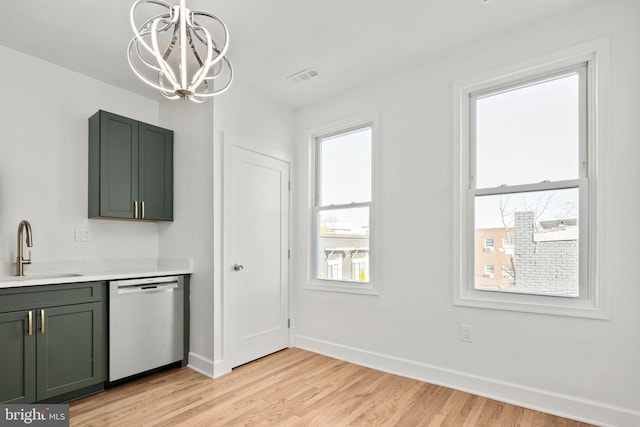 kitchen with sink, light hardwood / wood-style flooring, dishwasher, green cabinets, and pendant lighting