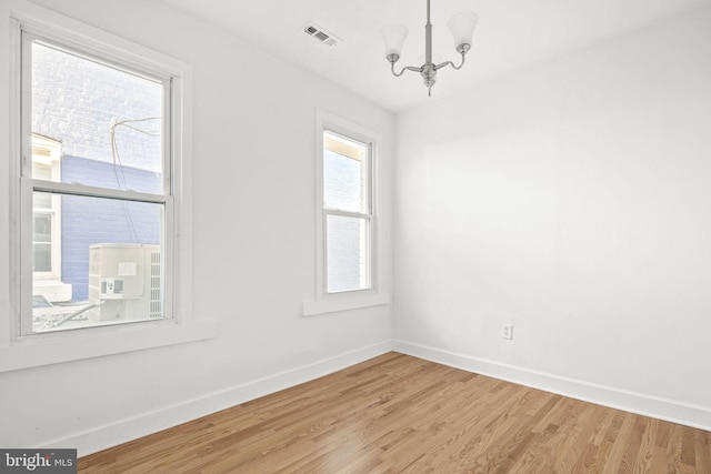 spare room featuring an inviting chandelier and wood-type flooring