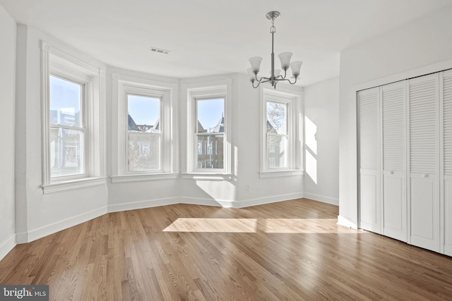 unfurnished dining area with a notable chandelier and light hardwood / wood-style flooring