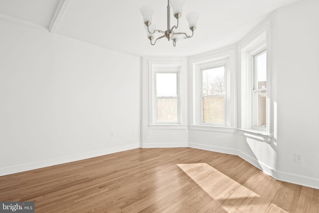 spare room with hardwood / wood-style floors and a notable chandelier