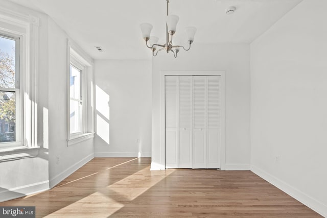 unfurnished dining area featuring a notable chandelier and light wood-type flooring