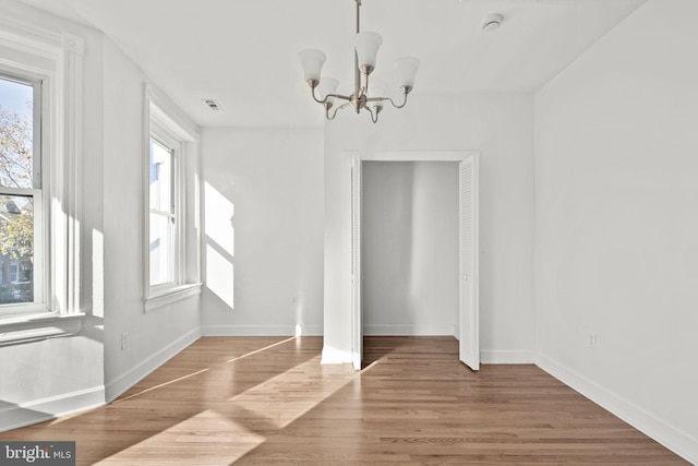 unfurnished dining area featuring wood-type flooring and a chandelier