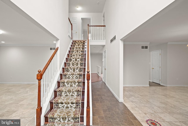 staircase with crown molding and a towering ceiling