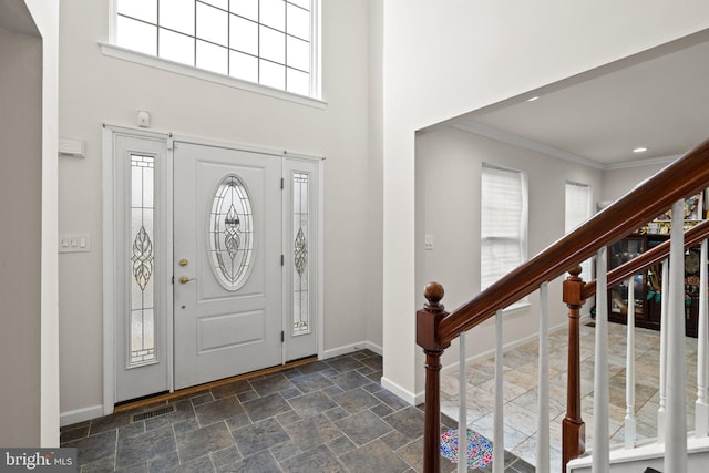 entrance foyer with crown molding and a towering ceiling