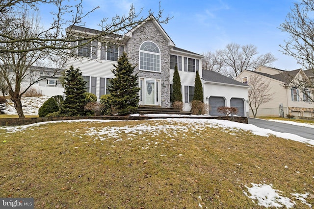 colonial inspired home with a garage and a lawn