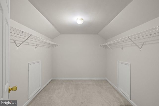 spacious closet with vaulted ceiling and light carpet