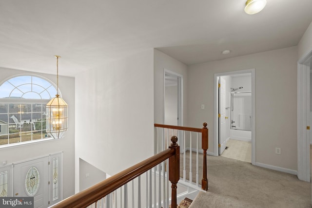 hall with light colored carpet and a notable chandelier