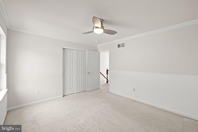 unfurnished bedroom with crown molding, light colored carpet, ceiling fan, and a closet