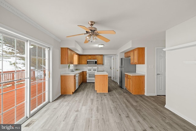 kitchen with ceiling fan, appliances with stainless steel finishes, a center island, and light hardwood / wood-style floors