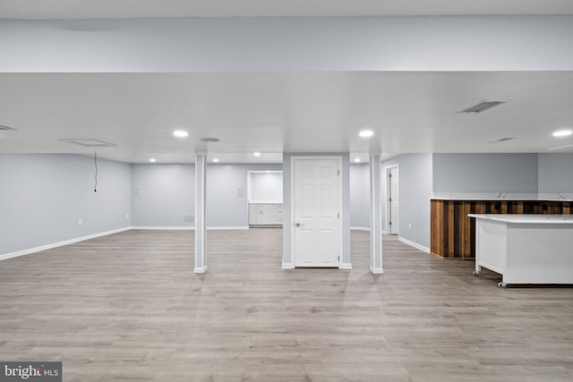 basement featuring bar area and light hardwood / wood-style floors