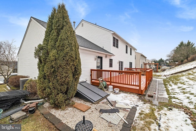 snow covered house with central AC and a wooden deck