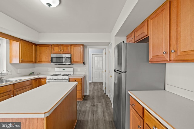 kitchen featuring a kitchen island, appliances with stainless steel finishes, sink, and dark wood-type flooring