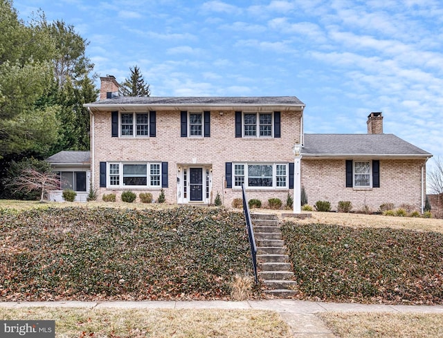 colonial home featuring brick siding and a chimney