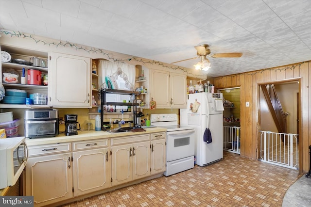 kitchen with ceiling fan, white appliances, wooden walls, and sink