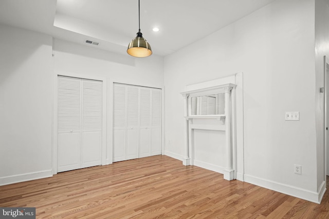 unfurnished bedroom with two closets and light hardwood / wood-style floors