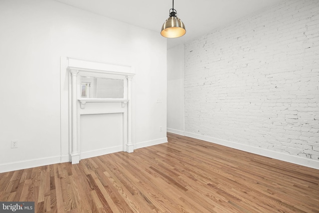 empty room with hardwood / wood-style flooring and brick wall