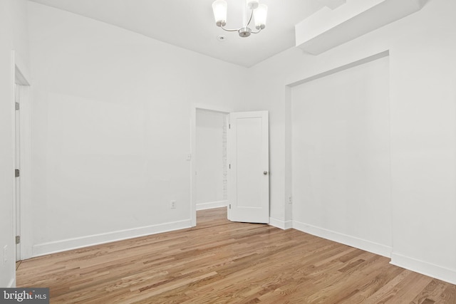 unfurnished room with an inviting chandelier and light hardwood / wood-style floors