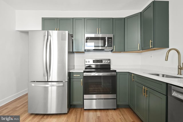 kitchen with stainless steel appliances, sink, and green cabinetry