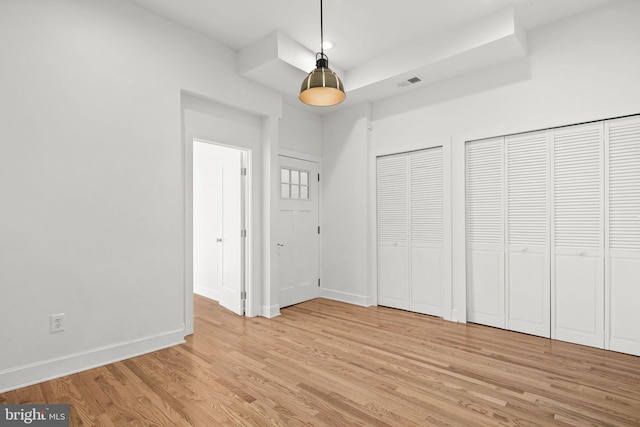 unfurnished bedroom featuring two closets and light hardwood / wood-style flooring