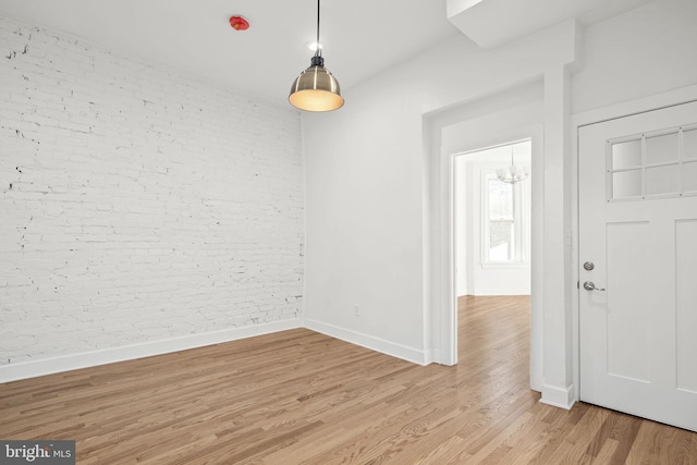 unfurnished dining area featuring brick wall and light hardwood / wood-style flooring