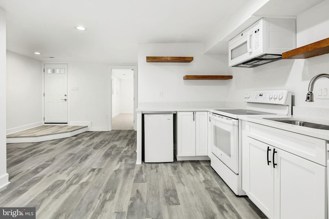 kitchen with white cabinetry, sink, white appliances, and light hardwood / wood-style flooring