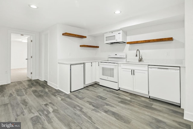 kitchen with white cabinetry, white appliances, light hardwood / wood-style floors, and sink